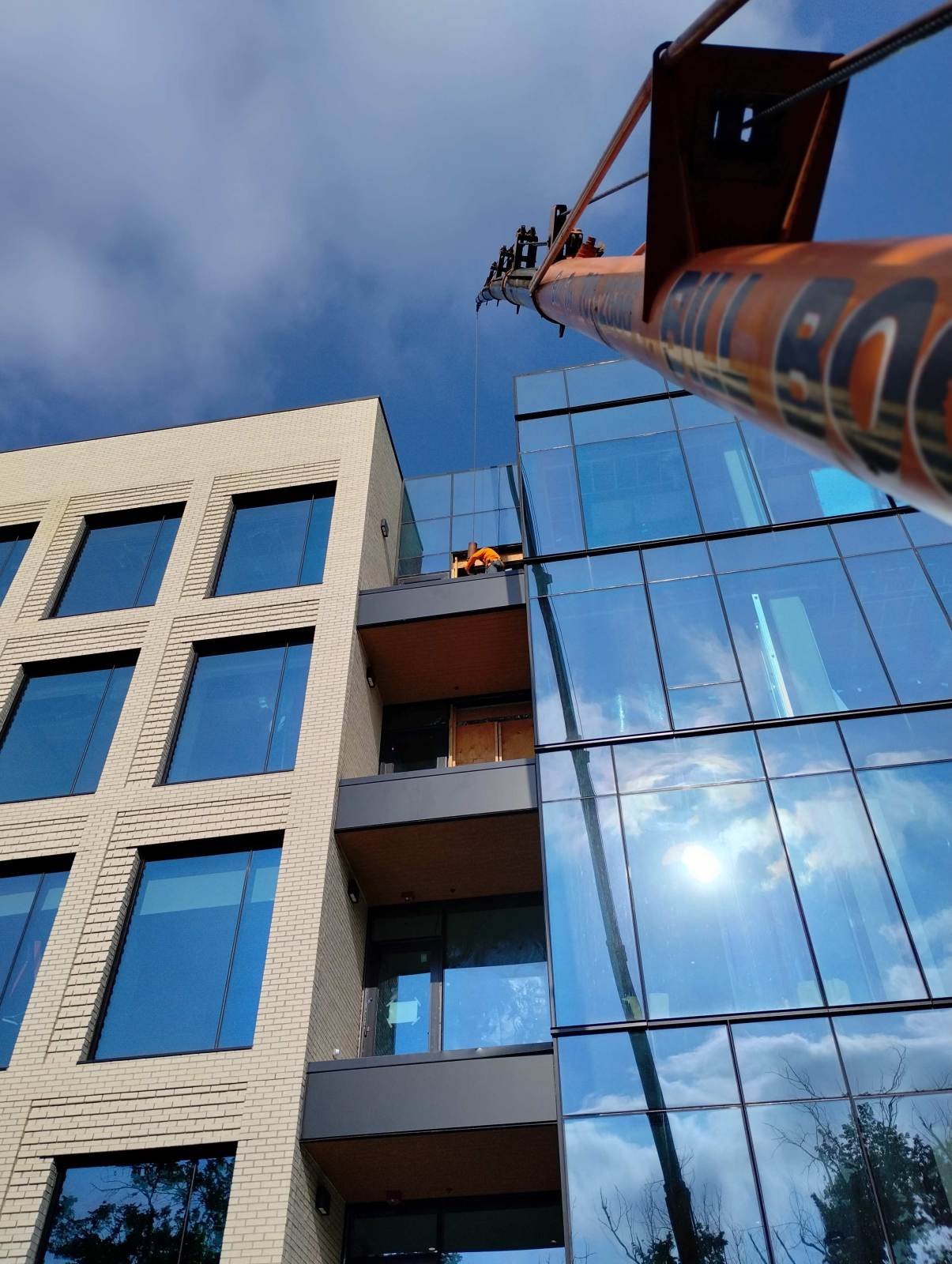 Bill Boom boom truck with boom extended alongside a glass mid-rise building