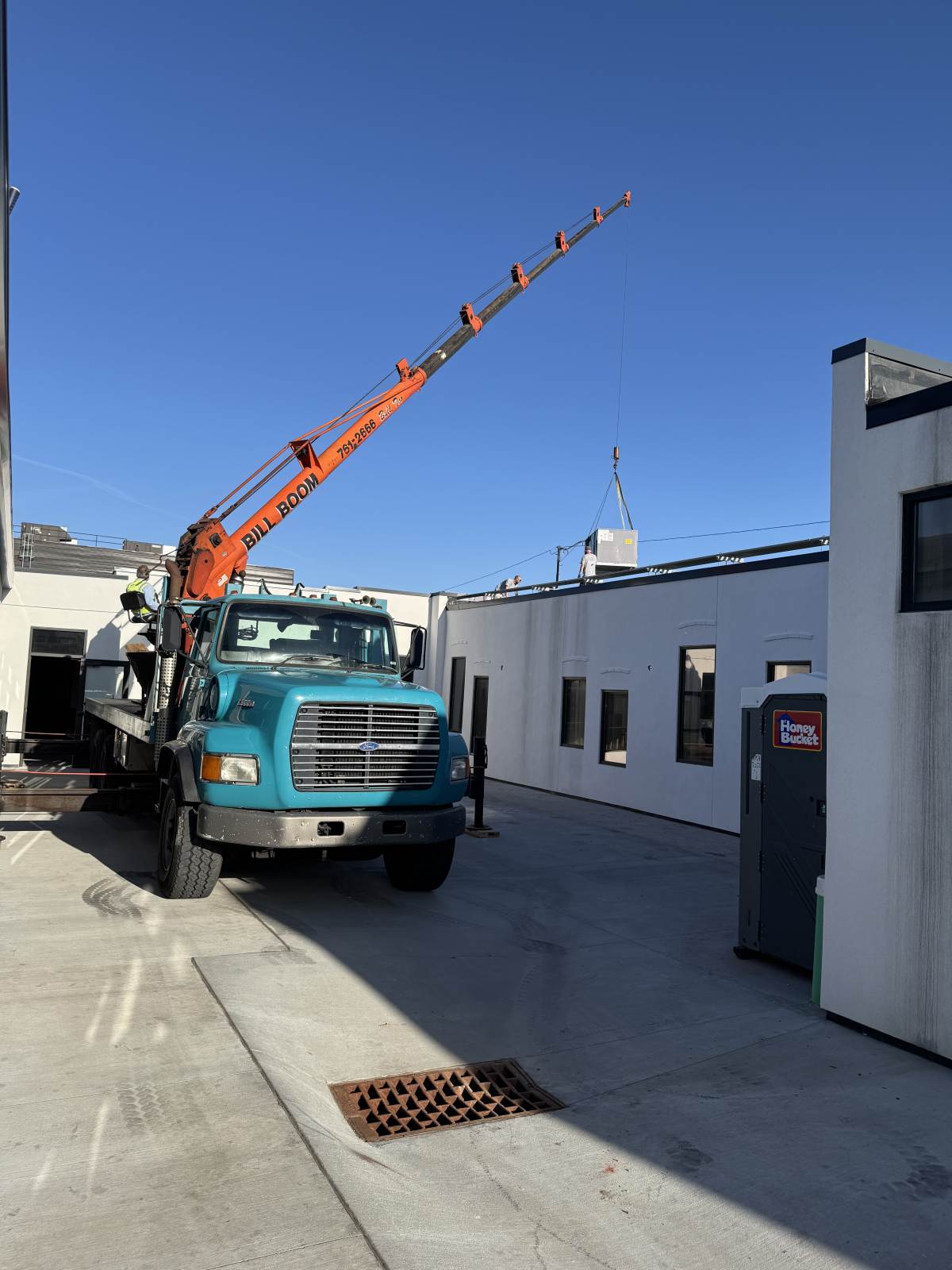 Bill Boom boom truck setting an HVAC package unit on a rooftop